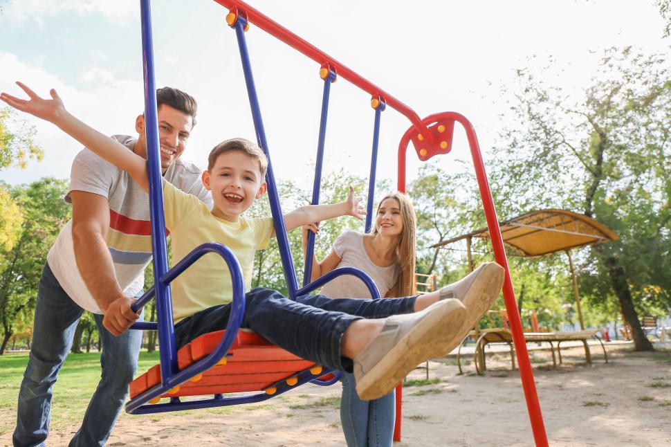 Mom and Dad with Son on Swing Set at Park